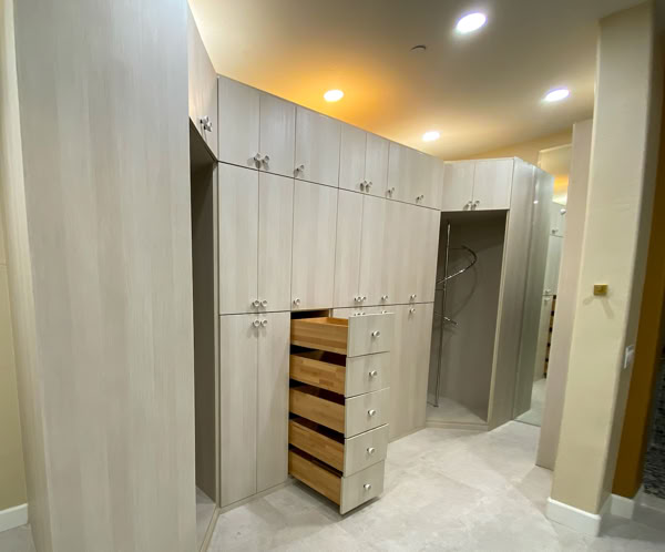 Wardrobe in hallway with mirrored wall reflecting furniture of modern kitchen in light apartment